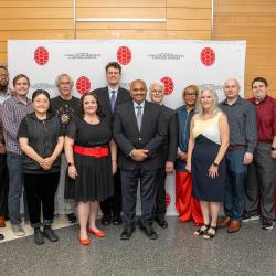 Group of employee awardees standing and smiling in front of a CMNS branded backdrop